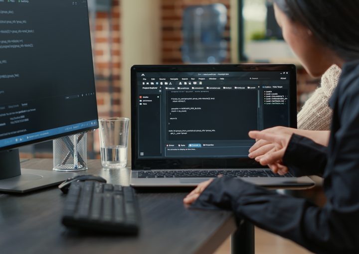 team programmers talking about algorithm running laptop screen pointing source code while sitting desk software developers collaborating data coding group project